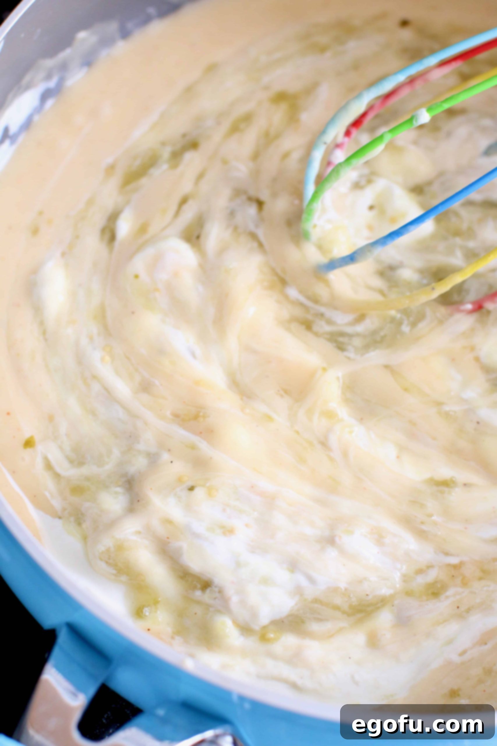 added sour cream and salsa verde into cream mixture being whisked together in a skillet.