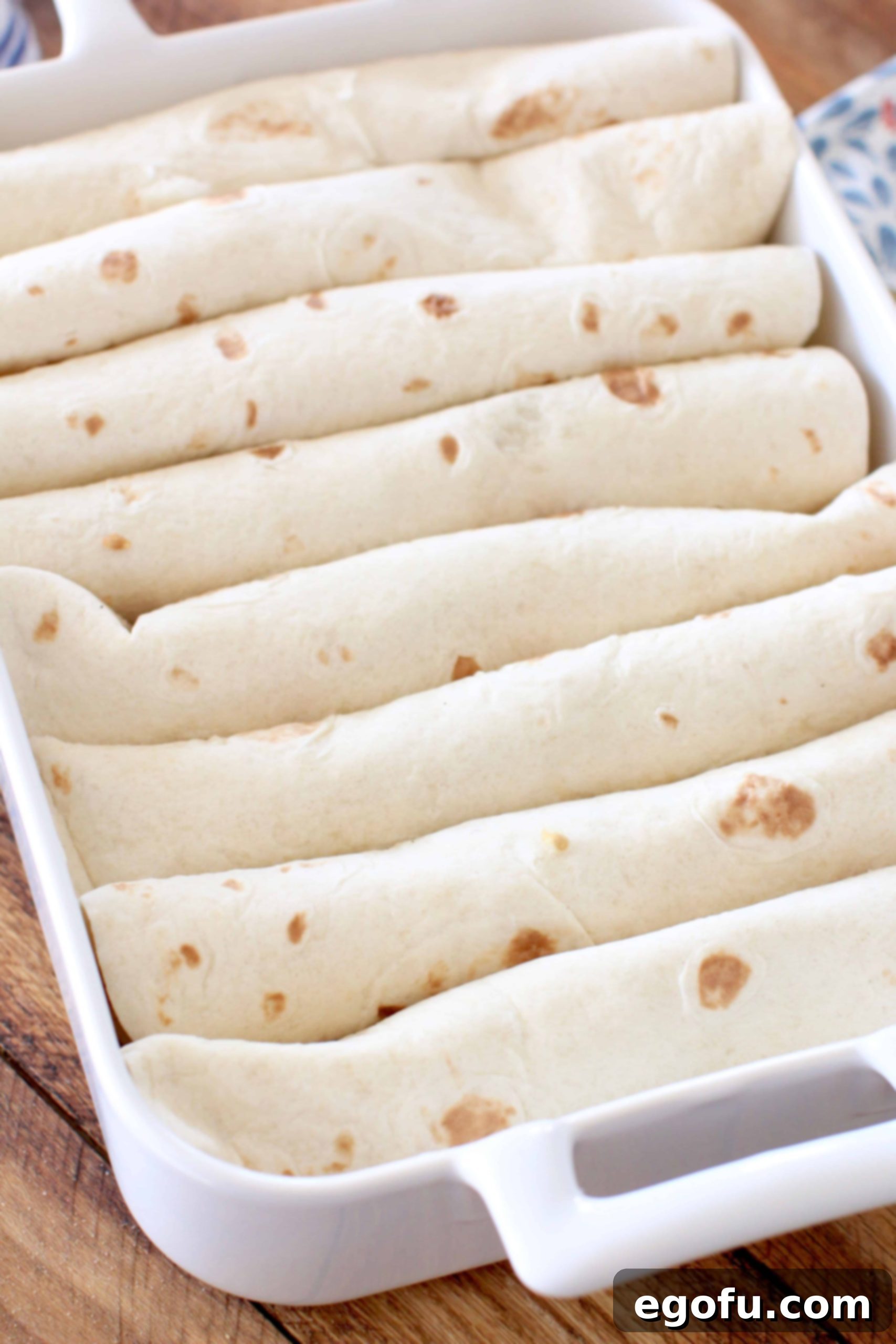 shrimp enchiladas rolled and placed into a white baking dish.