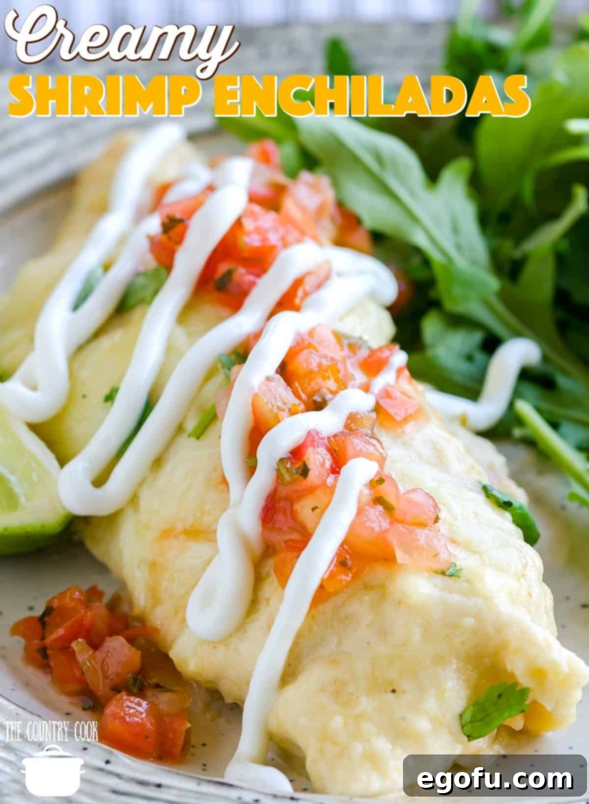 a closeup photo of creamy chrimp enchiladas topped with Pico de Gallo and a drizzle of sour cream.