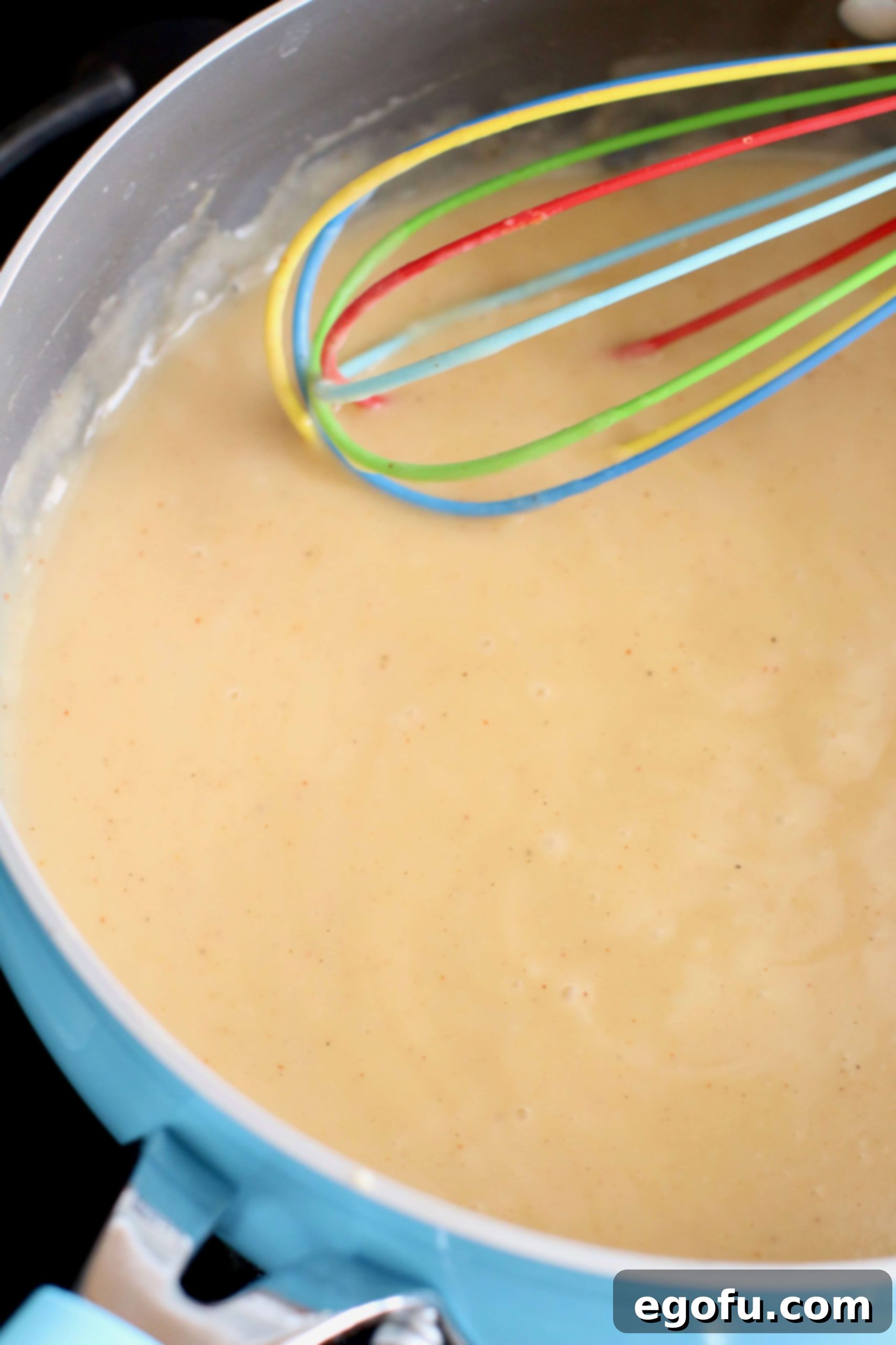 creamy sauce made with a roux and being whisked in a large skillet. 