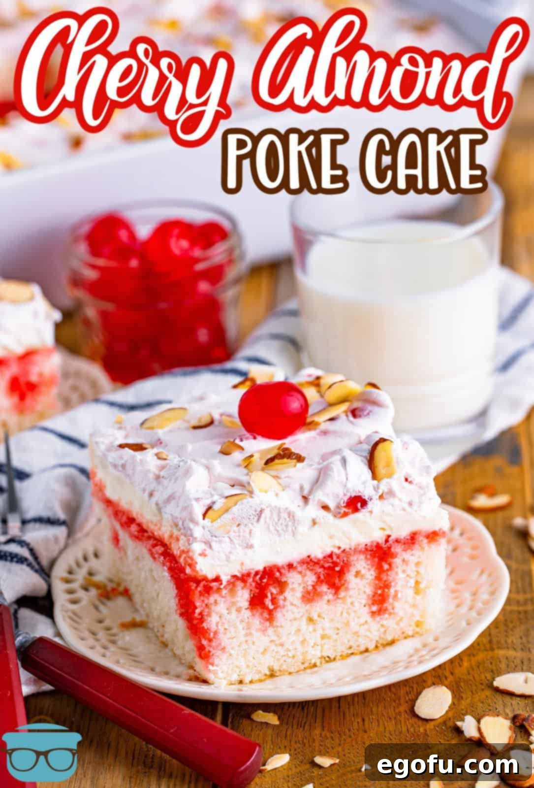 slice of Cherry Almond Poke Cake on a plate with a glass of milk shown in the background.