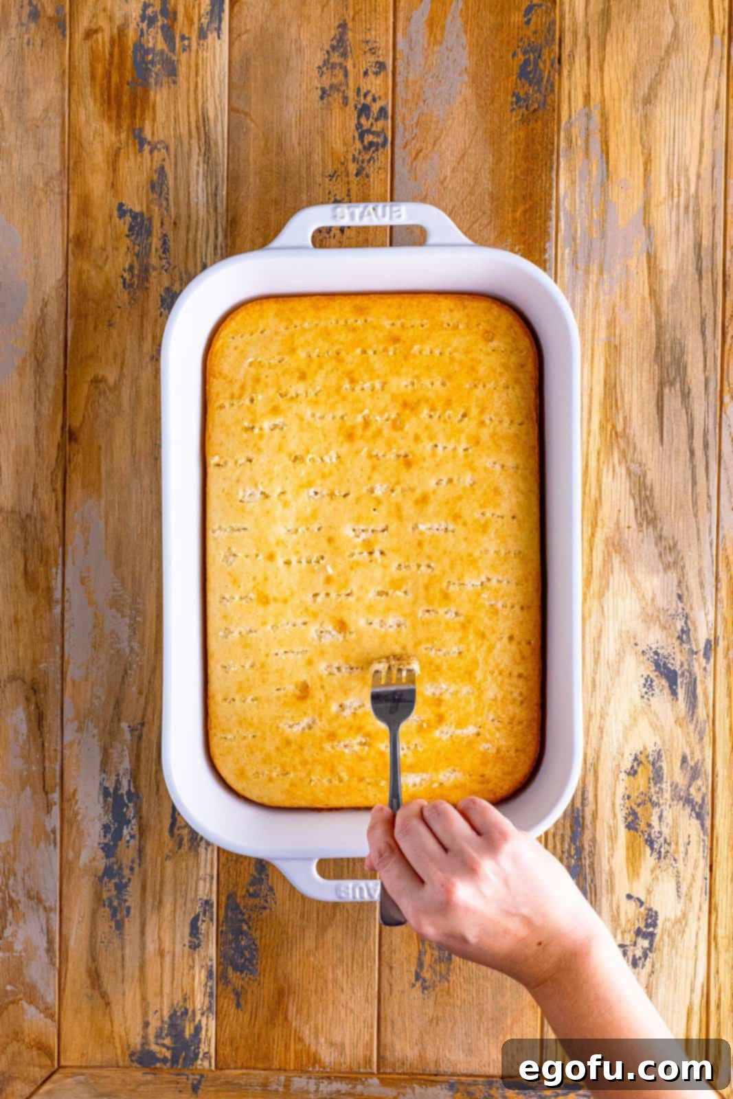 a fork poking holes in a baked cake. 