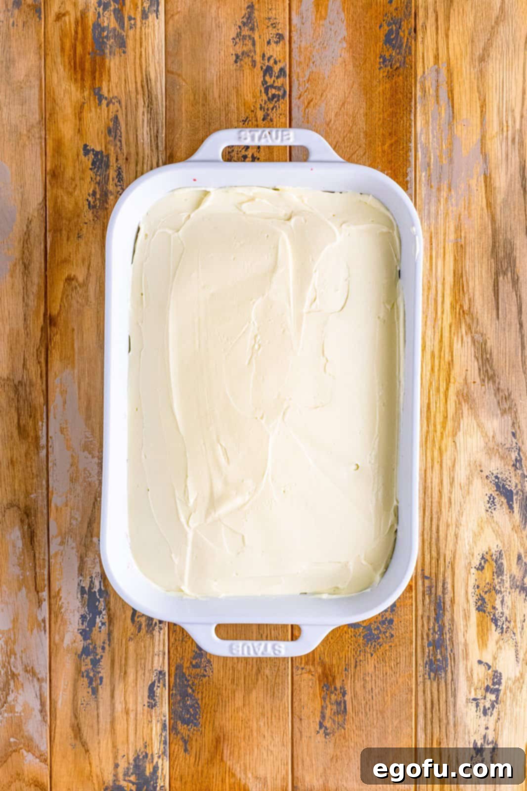 cream cheese frosting spread on top of baked cake.