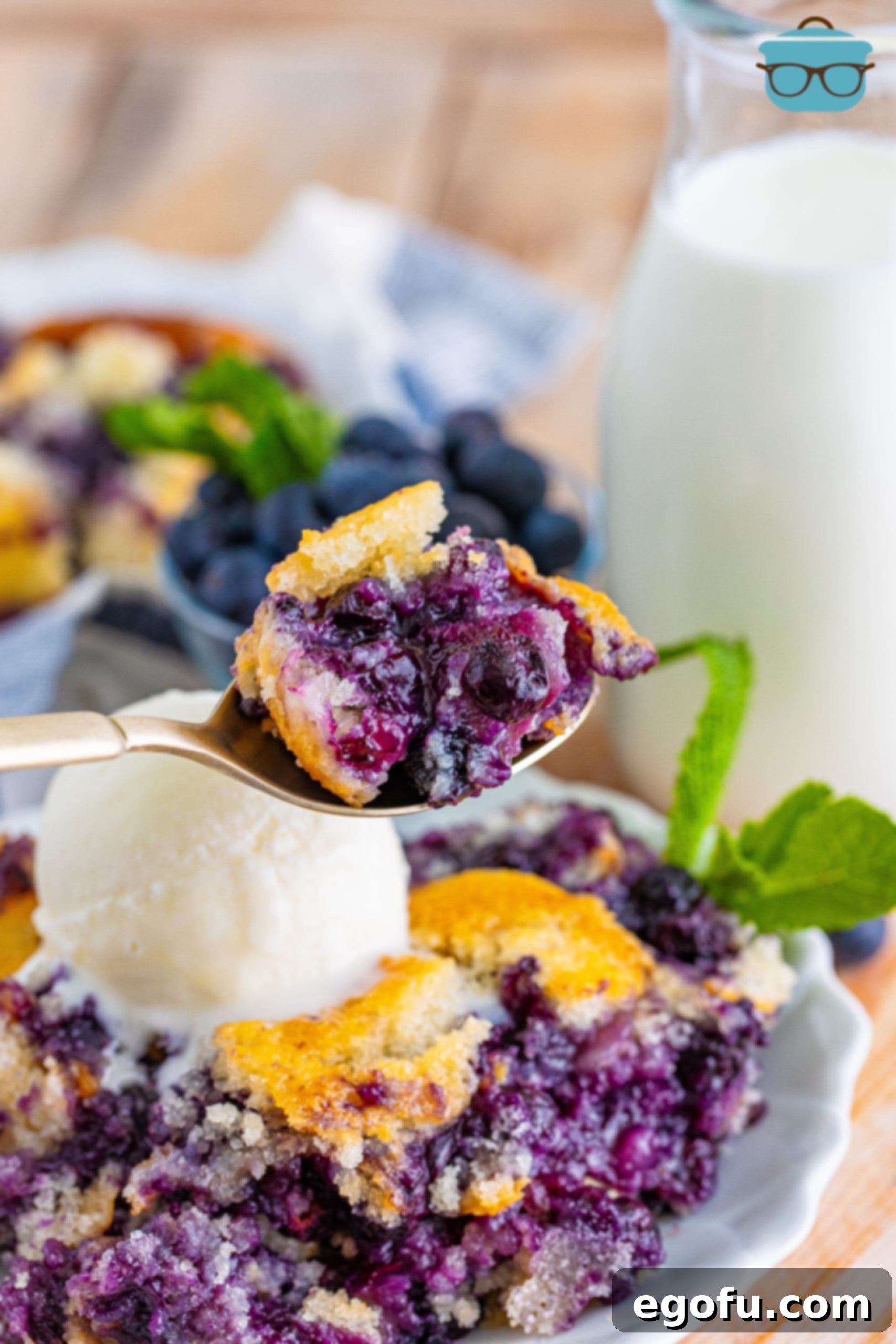 a spoon holding up a portion of blueberry cobbler. 