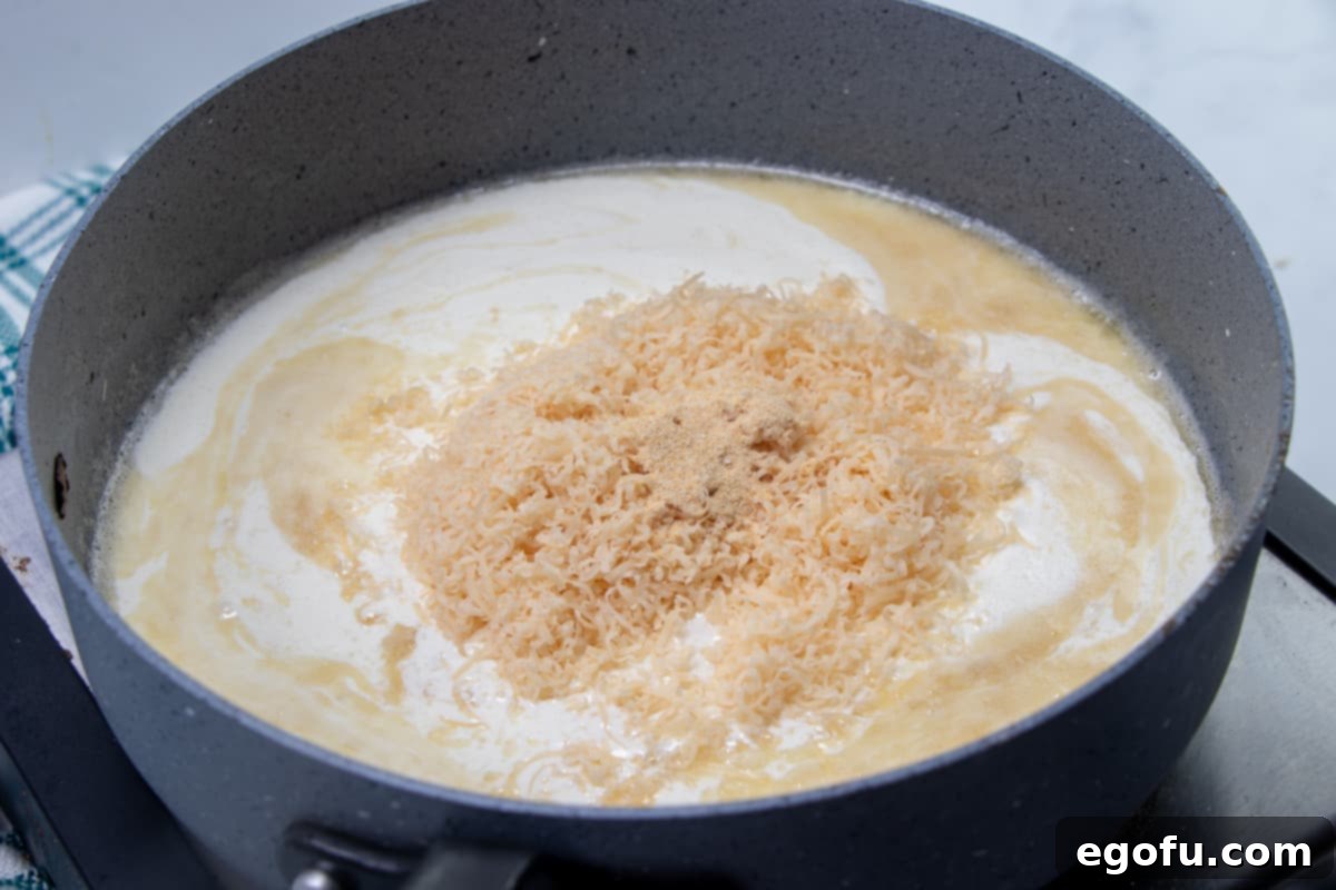Creamy Garlic Parmesan Fettuccine Alfredo 7 freshly grated Parmesan cheese added to heavy cream and roux mixture in a large skillet.