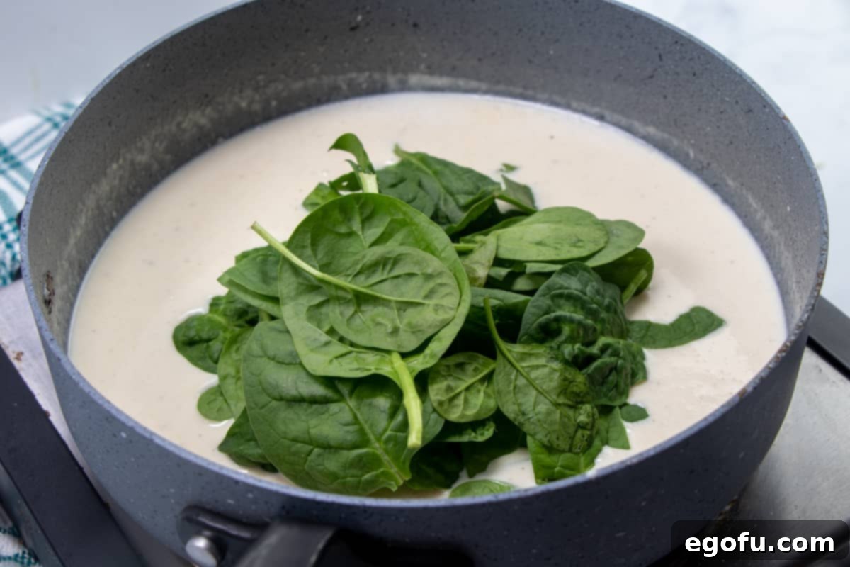 Creamy Garlic Parmesan Fettuccine Alfredo 8 fresh spinach leaves added to thick and creamy parmesan Alfredo sauce in a large skillet.