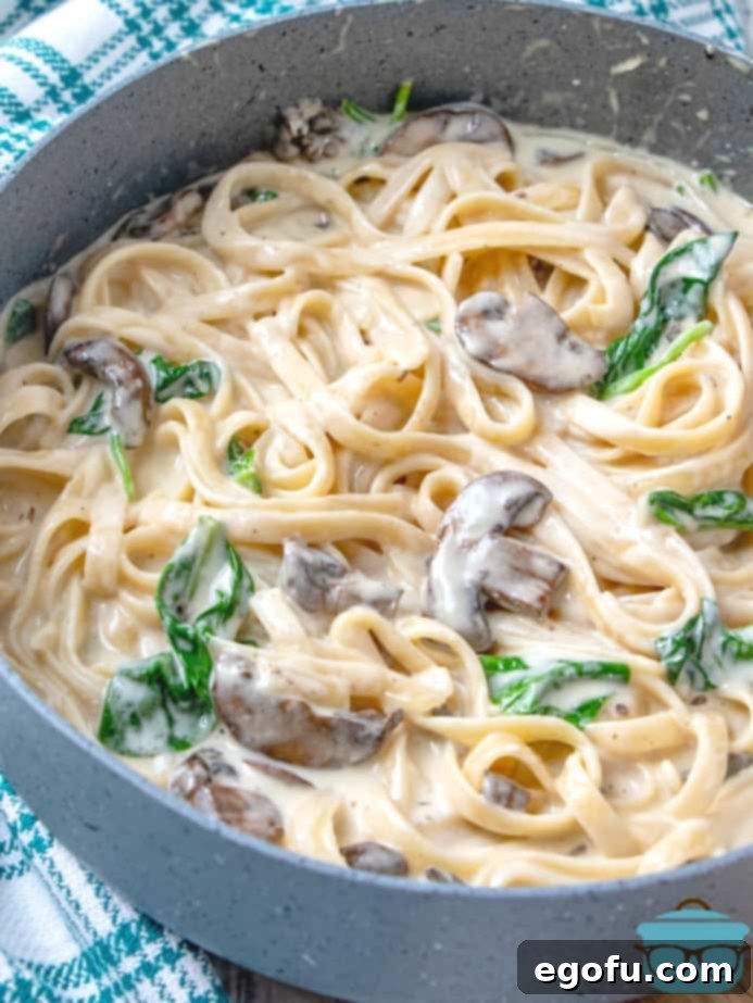 Creamy Garlic Parmesan Fettuccine Alfredo 10 Homemade Creamy Garlic Parmesan Fettuccine Alfredo with fresh spinach and mushrooms in a large skillet.