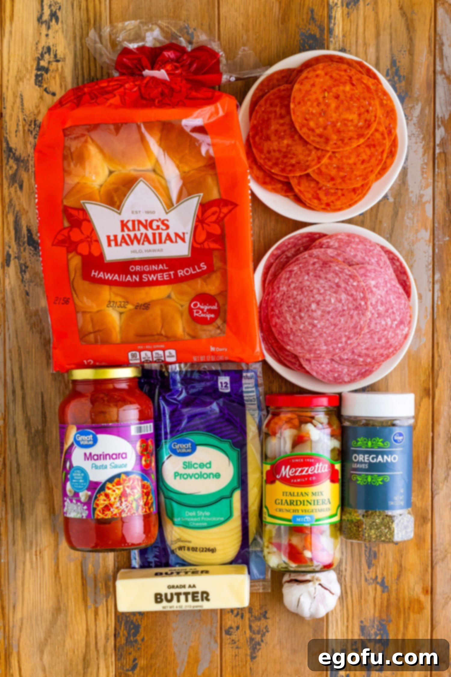All the ingredients laid out: Hawaiian rolls, pepperoni, salami, oregano, provolone cheese, butter, garlic, marinara, and giardiniera.