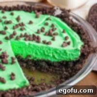 A slice of vibrant green grasshopper pie removed from a whole pie, showcasing its perfect texture and color.