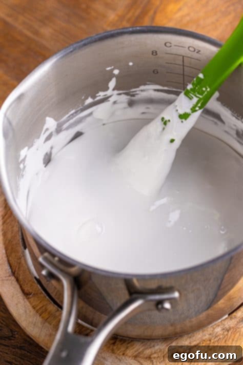 Green food coloring added to marshmallow fluff mixture in a bowl.