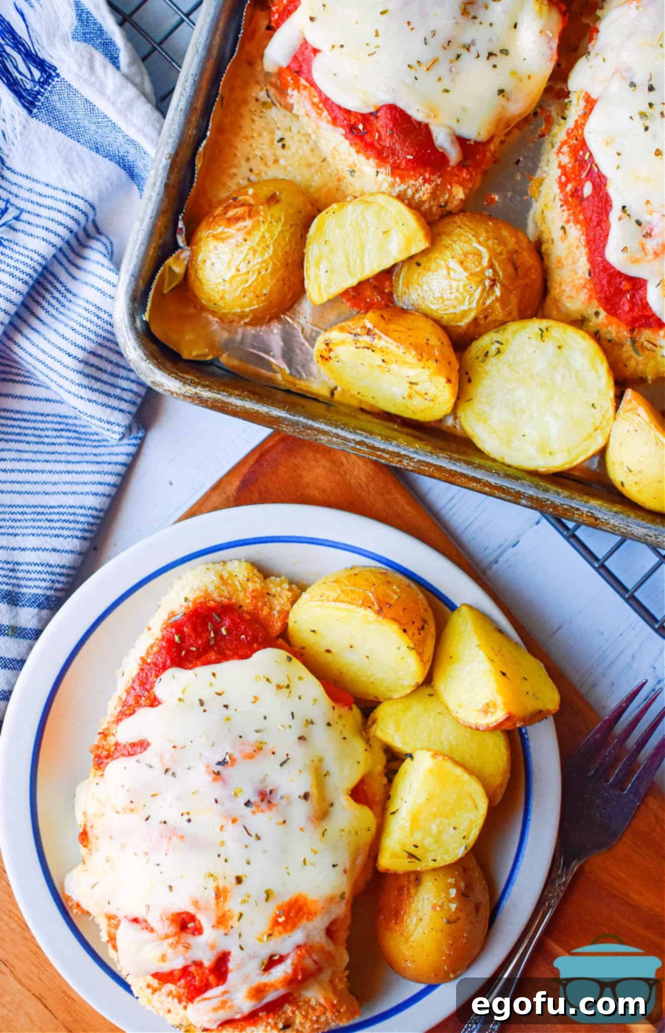 Fully baked sheet pan chicken parmesan shown on a small plate and served with roasted potatoes.