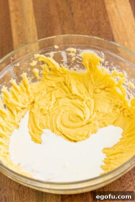 Sweet Blueberry Streusel Cake 14 Half and half is poured into the cake batter, showing the process of combining wet and dry ingredients in alternating steps.