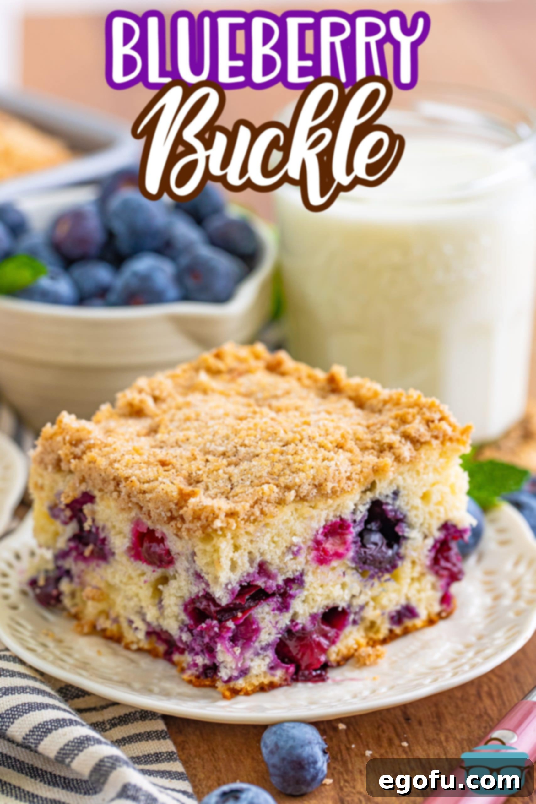 Sweet Blueberry Streusel Cake 3 A perfect slice of blueberry buckle cake is presented on a pristine white plate, with a tall glass of milk gently blurred in the background, suggesting a delightful pairing.