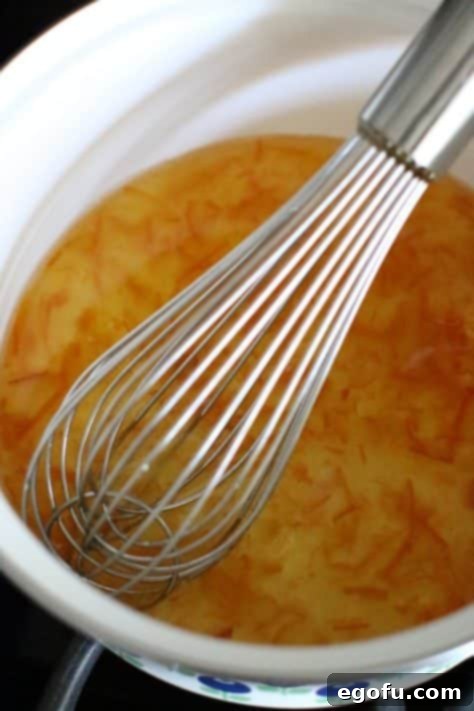 Orange marmalade with apple cider vinegar whisked together in a pot.