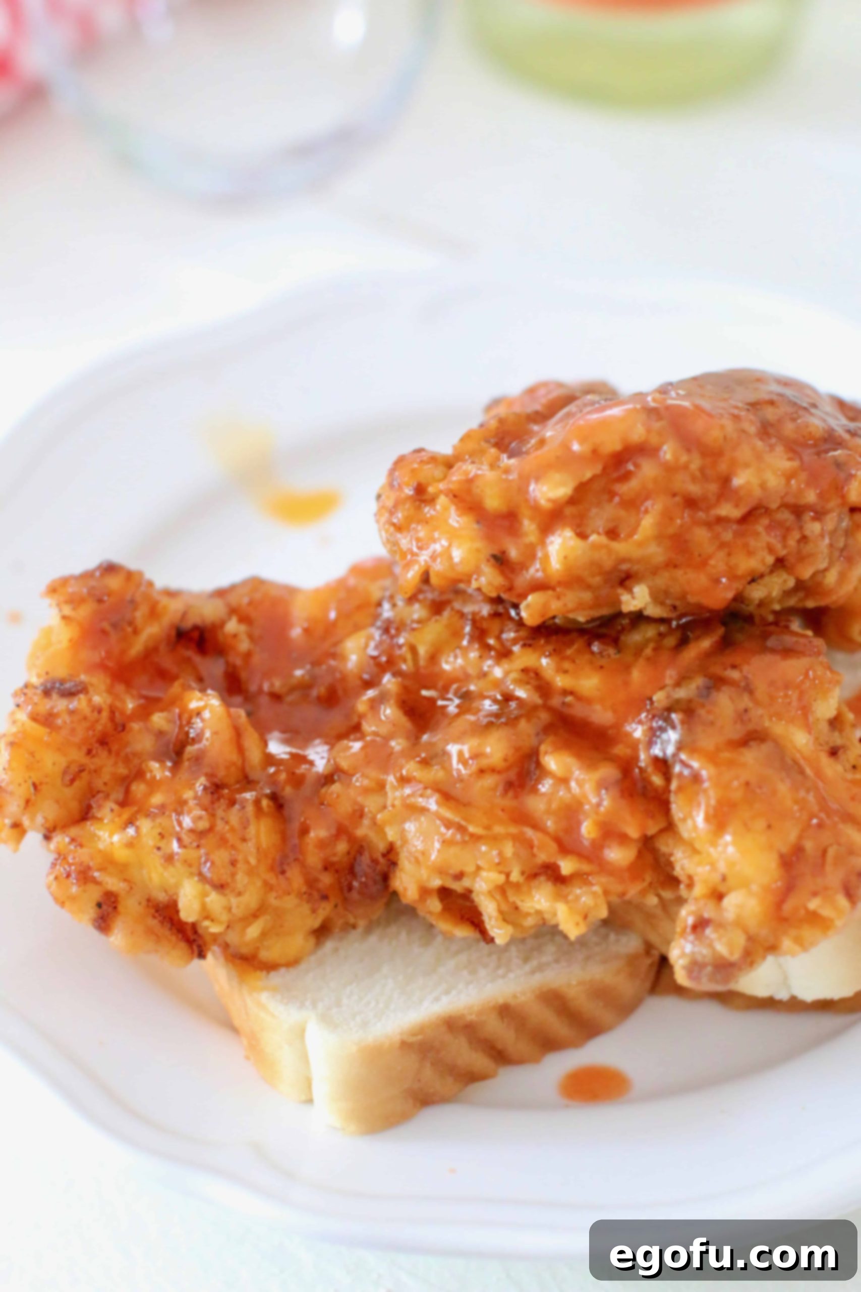 Nashville Hot Chicken sauce poured on top of crispy fried chicken breasts resting on white bread, ready for pickles.