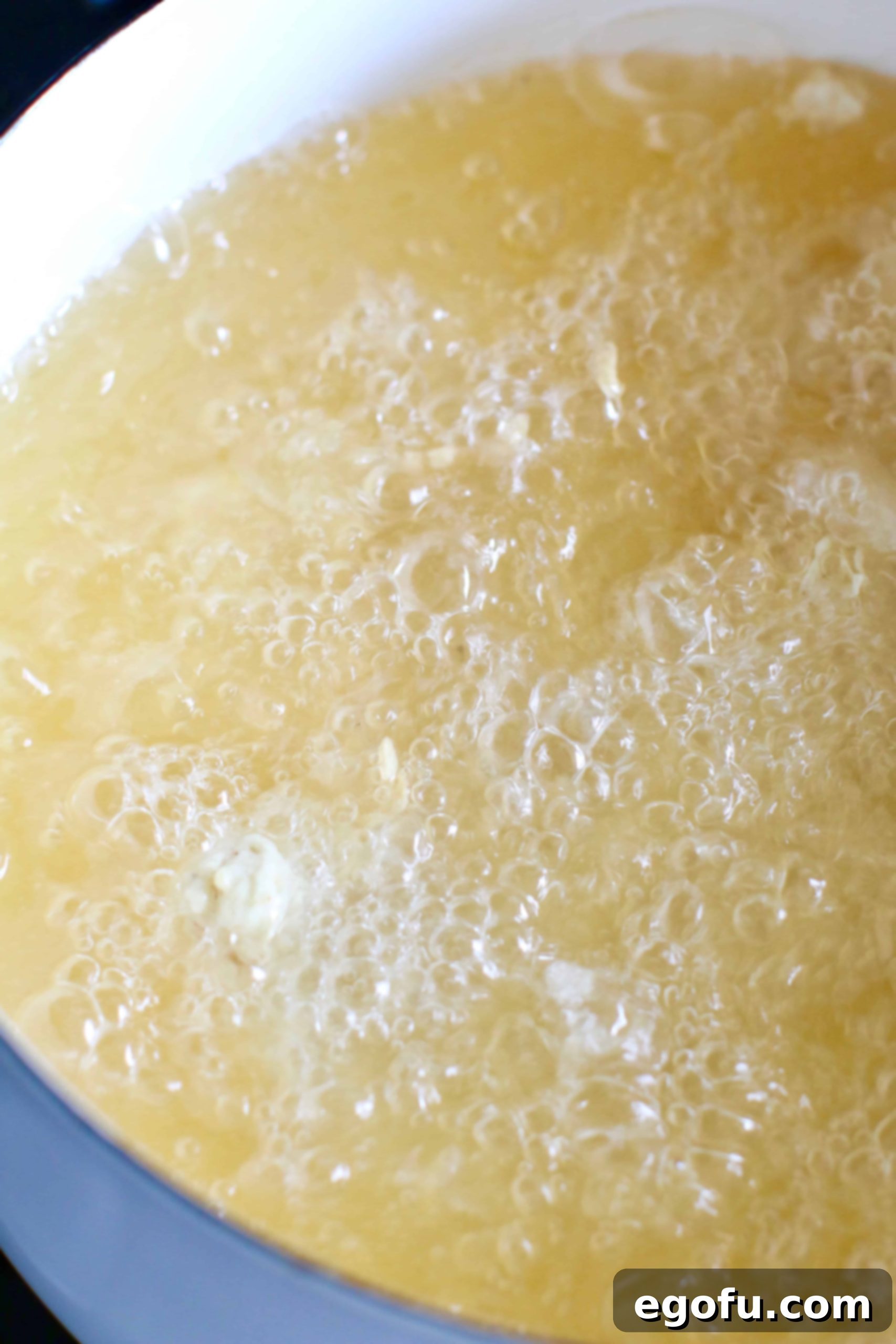 Chicken pieces frying in hot peanut oil, bubbling and browning.