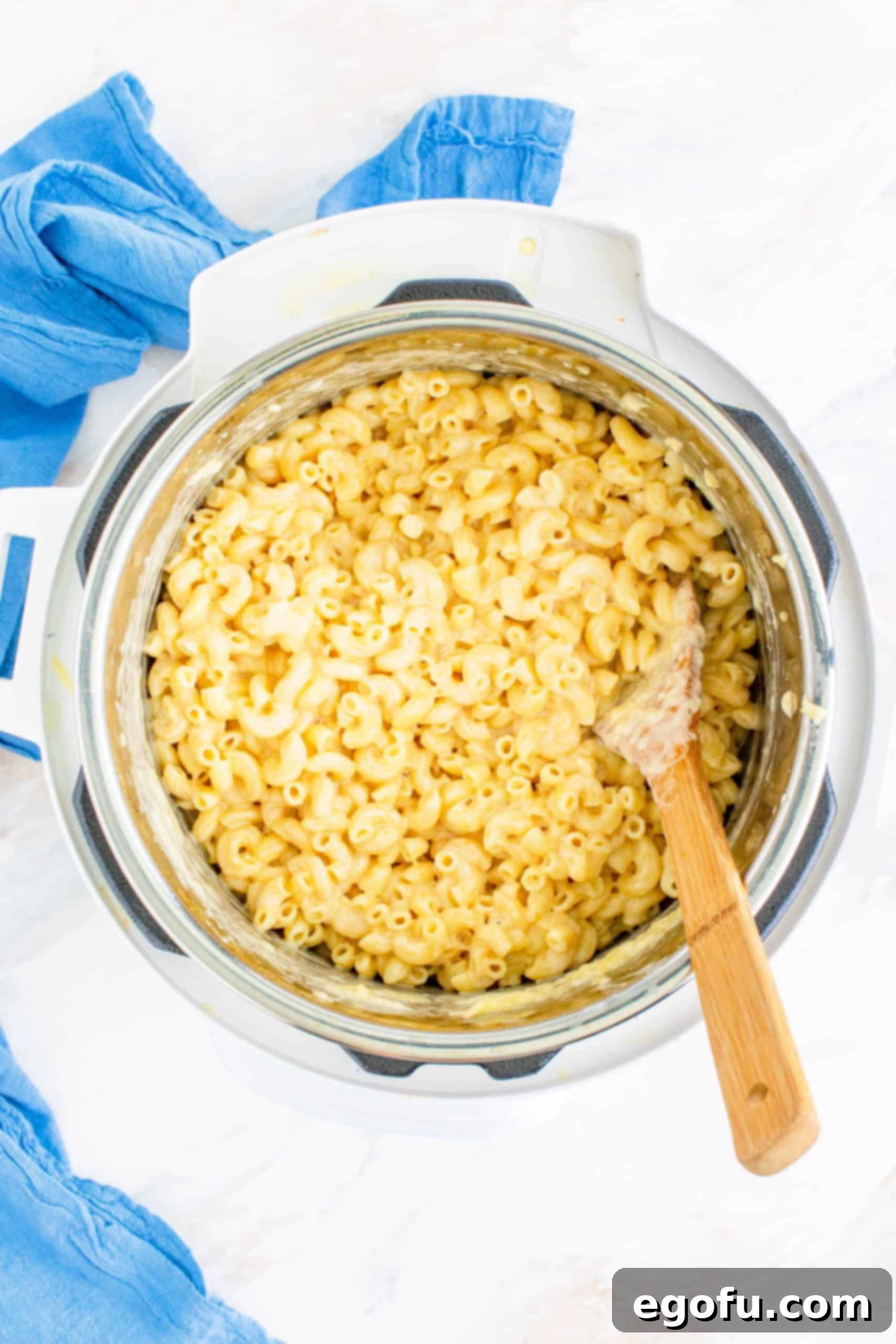 Milk, cheese, and macaroni noodles perfectly stirred together in an Instant Pot, showing the final creamy texture.