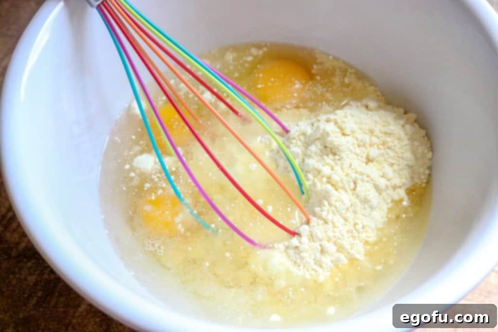 Smooth, prepared yellow cake mix batter poured into a baking pan over a layer of pineapple slices.