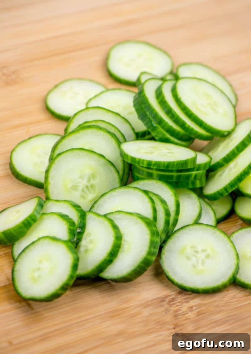 Freshly sliced English cucumber for salad preparation, ready to be seasoned.