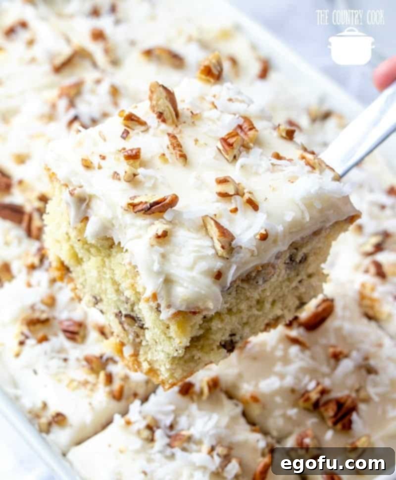 A serving spatula lifts a perfect slice of Italian Cream Cake from the white baking dish, ready to be enjoyed.