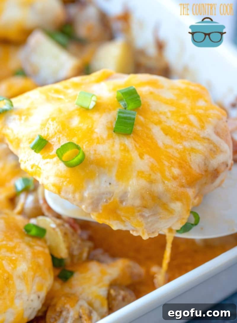 Loaded Cheesy Bacon Chicken and Roasted Potatoes 12 a spatula holding up a melted cheese coated chicken breast.