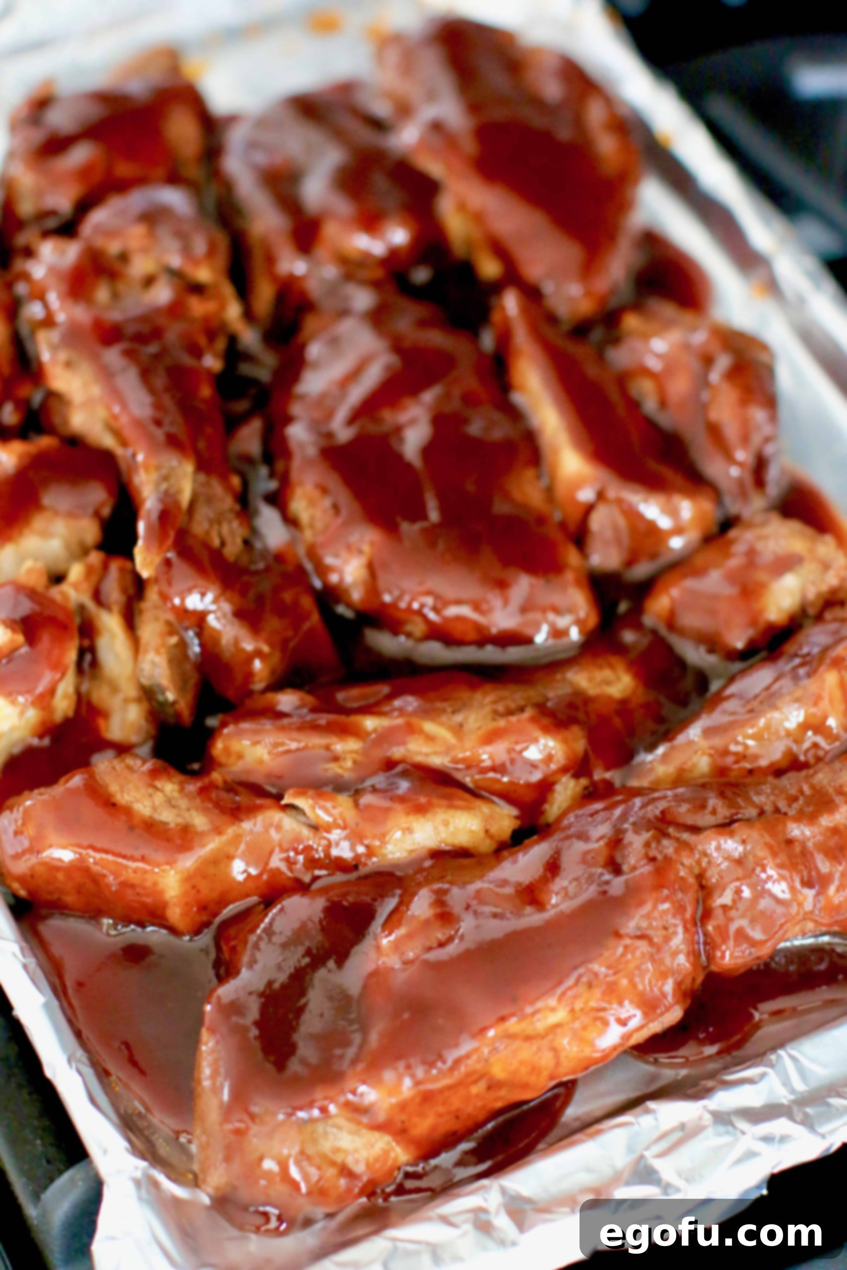 Instant Pot Tender Korean BBQ Country Ribs 18 Korean BBQ sauce poured over cooked country style ribs on a baking sheet.