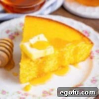 Looking down on a triangle piece of Sweet Cornbread with some butter and honey drizzled on top.