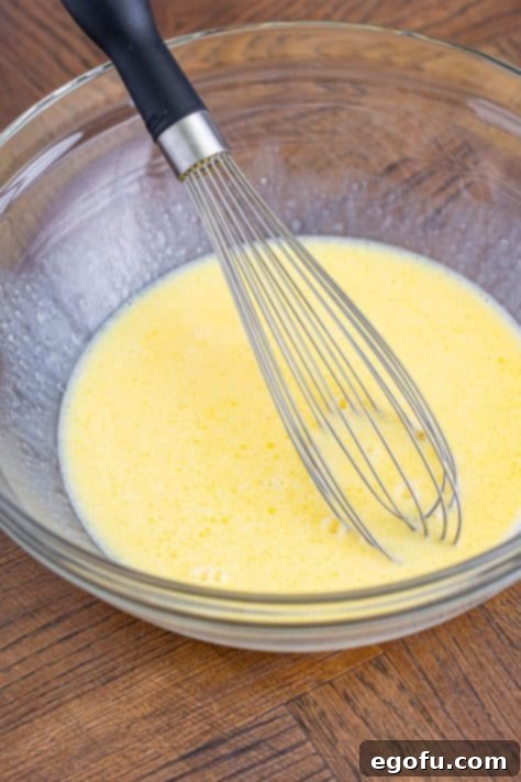 The wet ingredients for Sweet Cornbread and a whisk in a bowl.