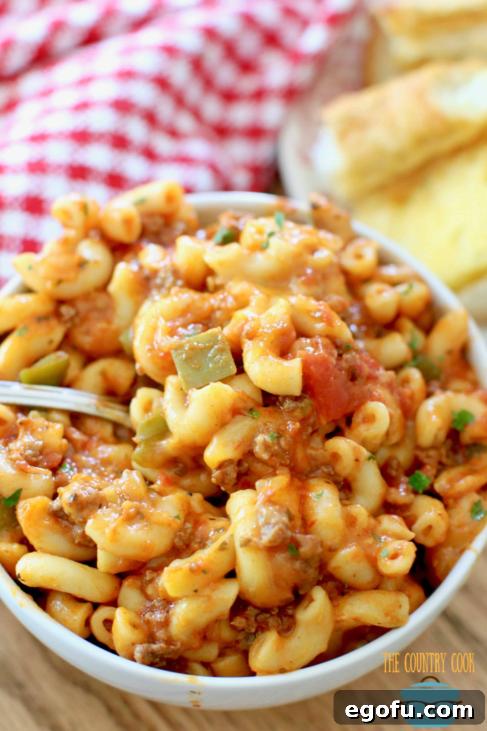 Hearty Instant Pot American Goulash 12 Instant Pot American Goulash served in a white bowl, generously topped with shredded cheese and a side of crispy garlic bread, perfect for a comforting meal.