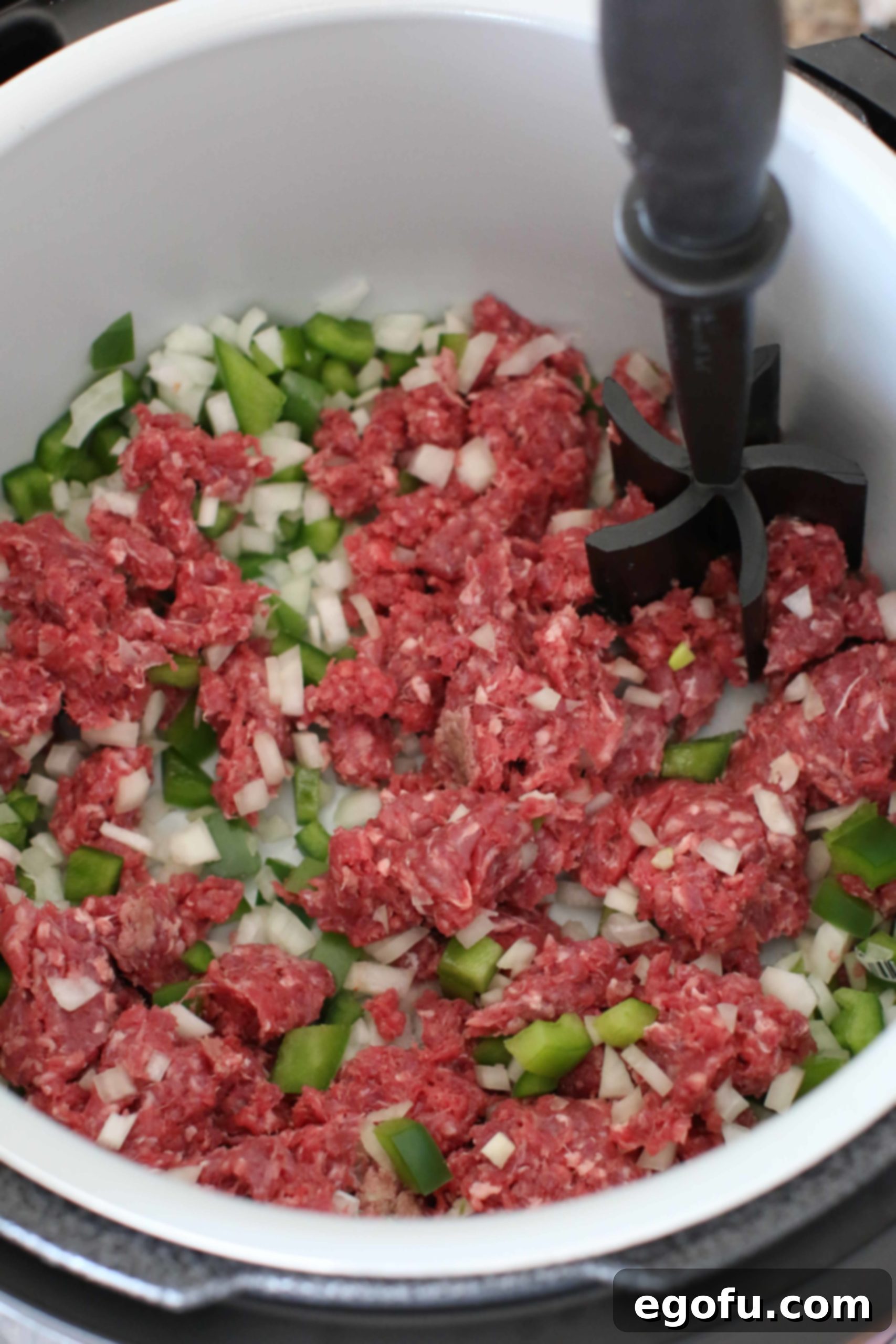 Hearty Instant Pot American Goulash 6 Ground beef, diced onion, and green pepper browning and crumbling in an 8-quart electric pressure cooker on the sauté setting, preparing the base for Instant Pot American Goulash.