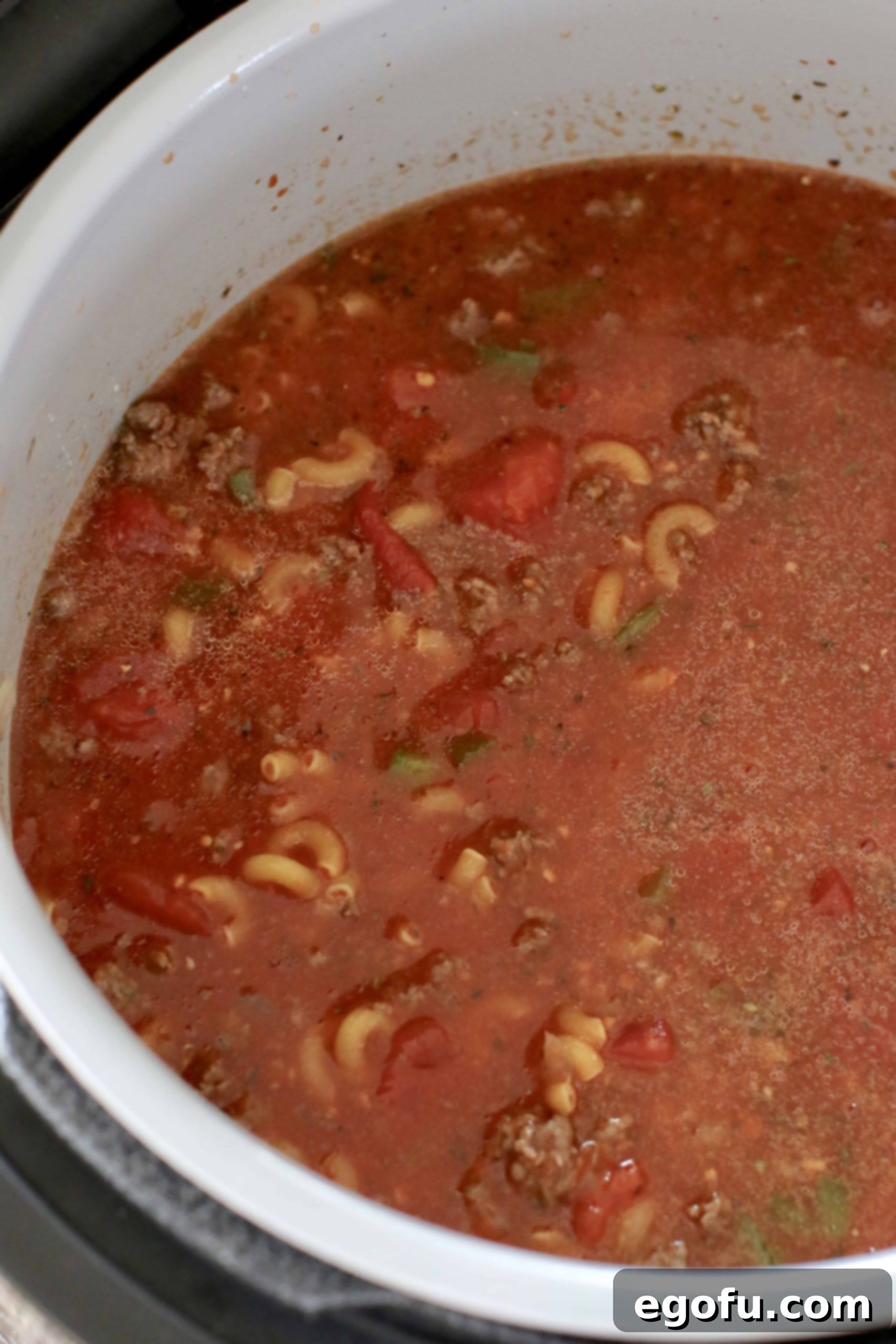 Hearty Instant Pot American Goulash 8 All the ingredients for Instant Pot Goulash layered inside an 8-quart electric pressure cooker, including ground beef, diced tomatoes, spaghetti sauce, water, and uncooked macaroni noodles, ready for pressure cooking.