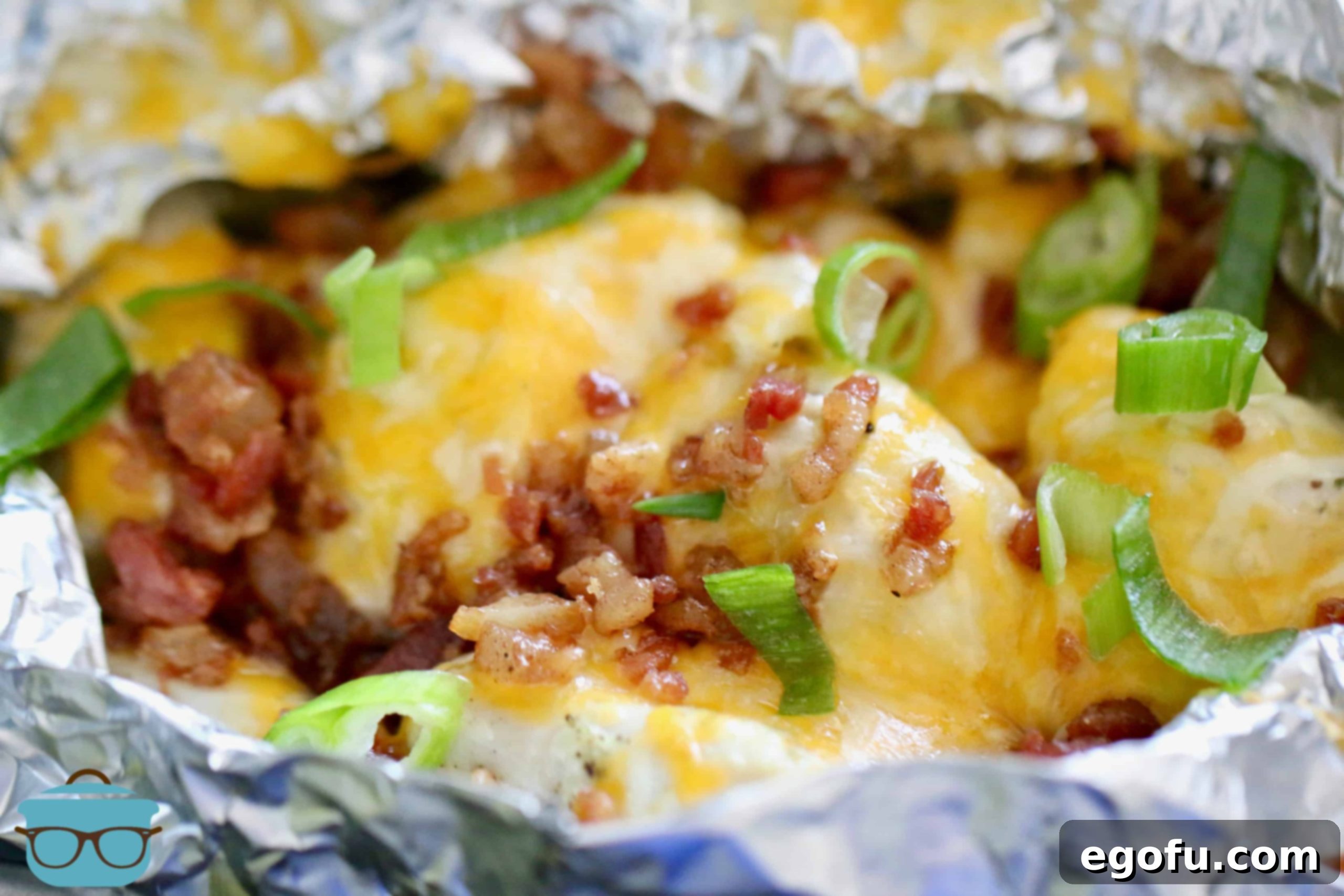 Opened Chicken Potato Foil Packets, showcasing the tender chicken and potatoes, topped with melted cheese and crispy bacon, fresh out of the oven.