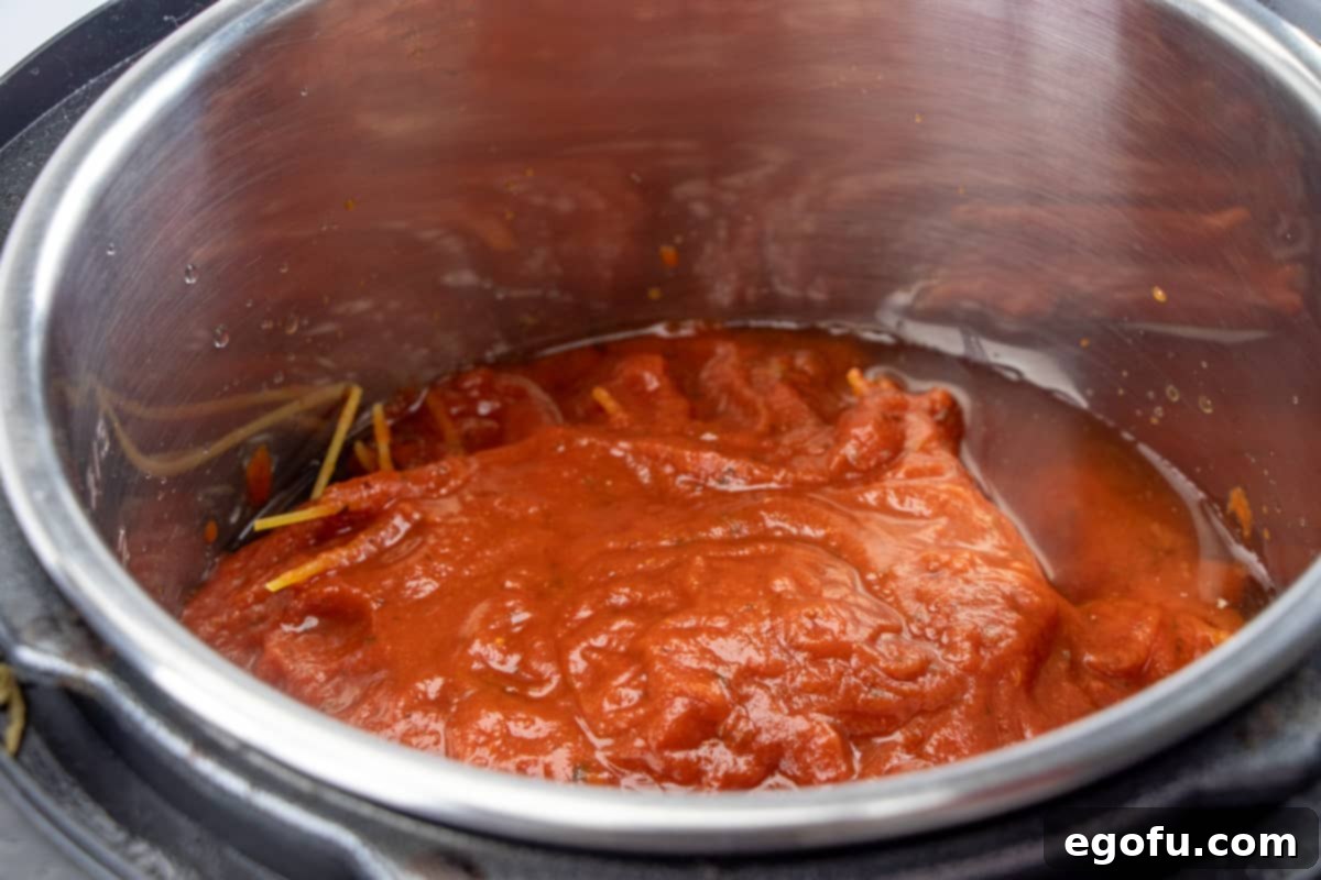 One-Pot Wonder: Instant Pot Spaghetti & Meatballs 7 spaghetti sauce, water and broth on top of spaghetti noodles and frozen meatballs in the bottom of an Instant Pot.