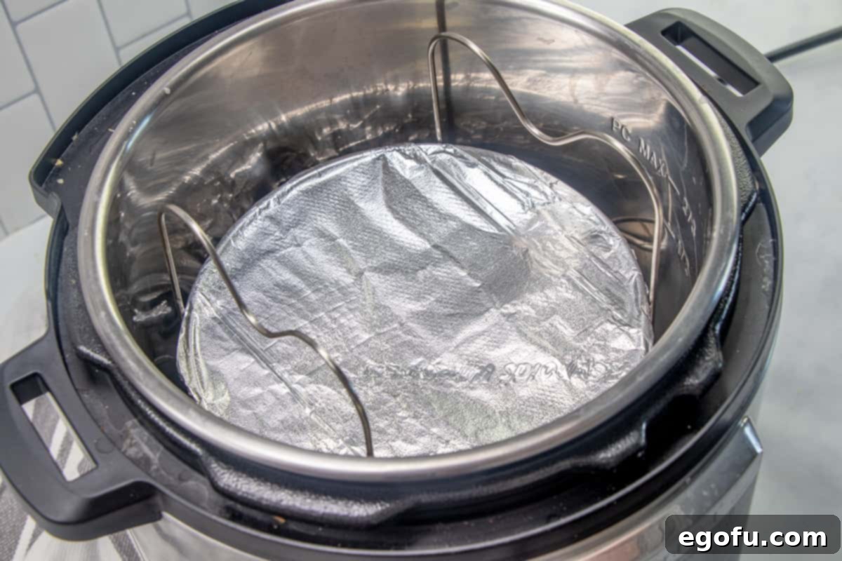 The Ultimate Instant Pot Cheesecake 11 foil covered springform pan placed in a trivet inside a 6-quart electric pressure cooker.