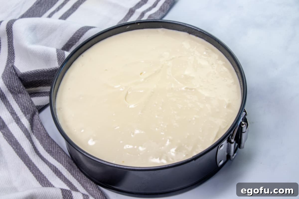 The Ultimate Instant Pot Cheesecake 9 cheesecake batter poured into prepared graham cracker crust in a springform pan.