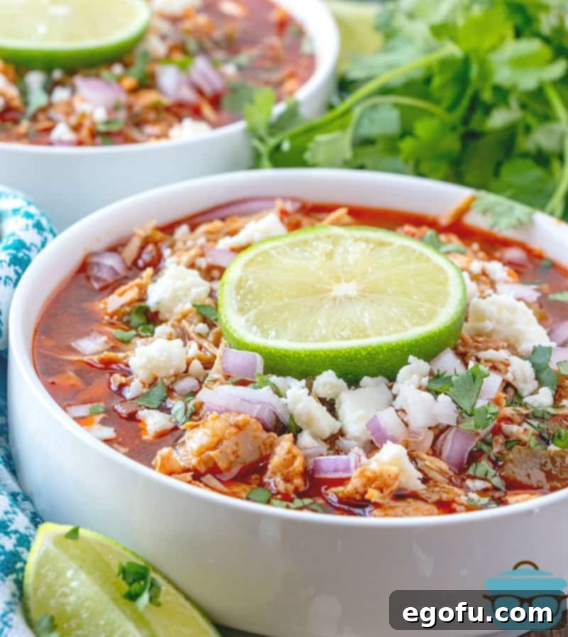 Finished Instant Pot Pork Chili topped with Cotija cheese, diced red onions, cilantro, and a fresh lime wedge.