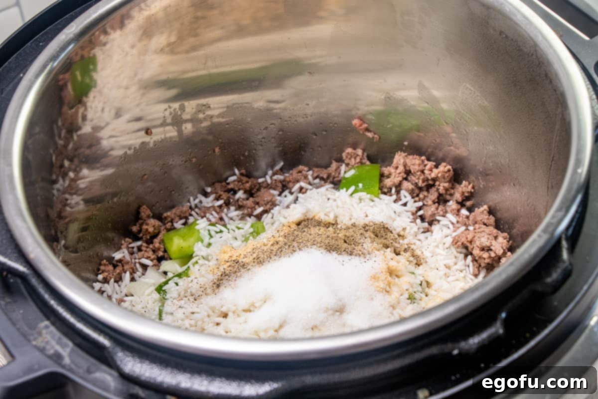 Deconstructed Stuffed Pepper Soup 6 The Instant Pot contains cooked ground beef, now with diced onion, green bell peppers, rinsed uncooked long-grain rice, sugar, garlic powder, salt, and pepper added and stirred together.
