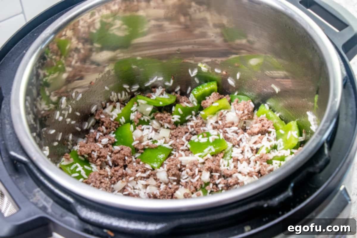 Deconstructed Stuffed Pepper Soup 7 Close-up shot of fully cooked ground beef, green peppers, and onions stirred together with rice and seasonings in the Instant Pot, after a brief sauté, with visible steam.