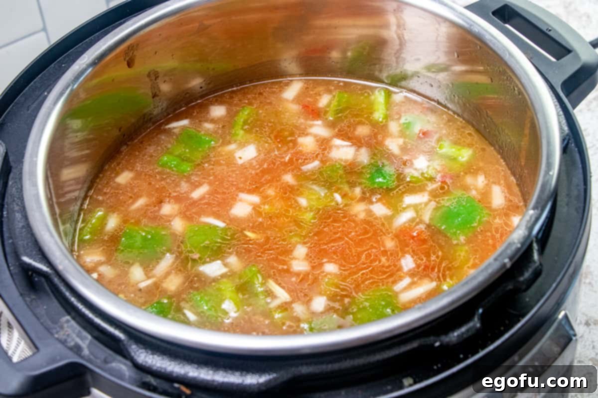 Deconstructed Stuffed Pepper Soup 8 Chicken broth, diced tomatoes, and condensed tomato soup are being poured into and gently stirred with the ground beef and vegetable mixture in the Instant Pot, forming the liquid base of the soup.