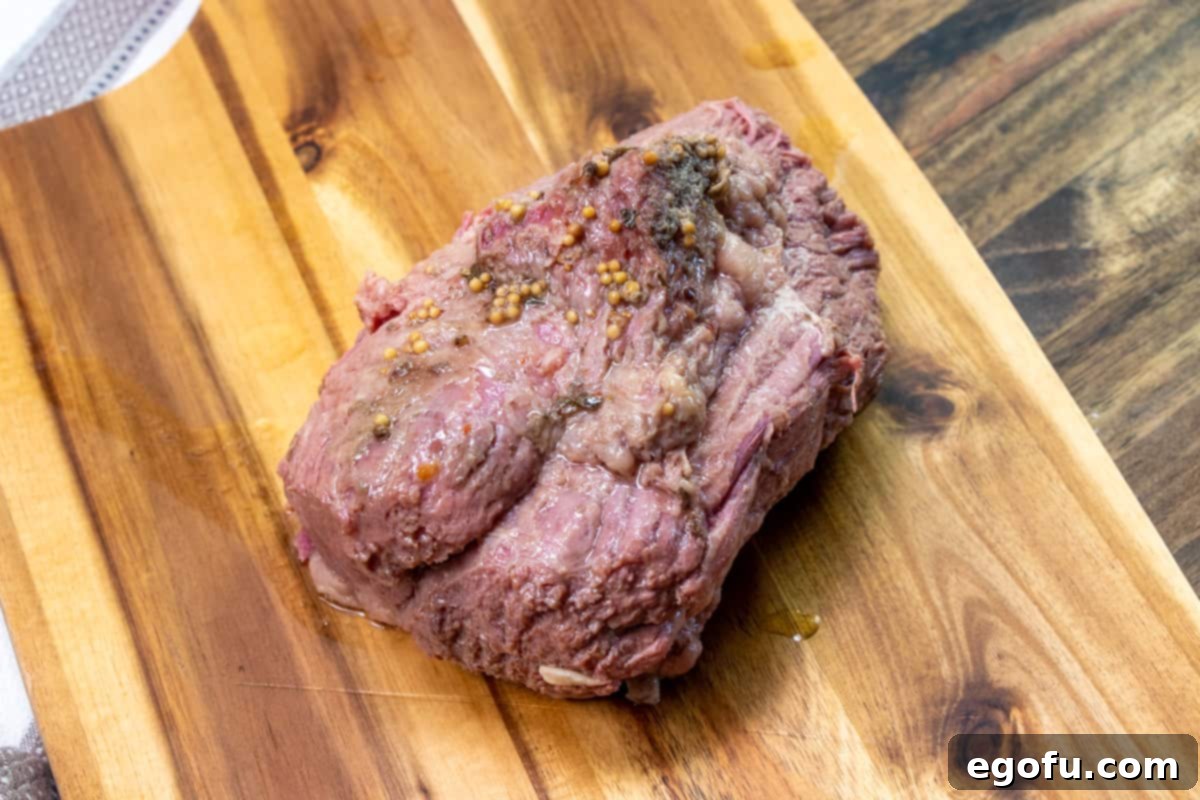 fully cooked corned beef resting on a cutting board.