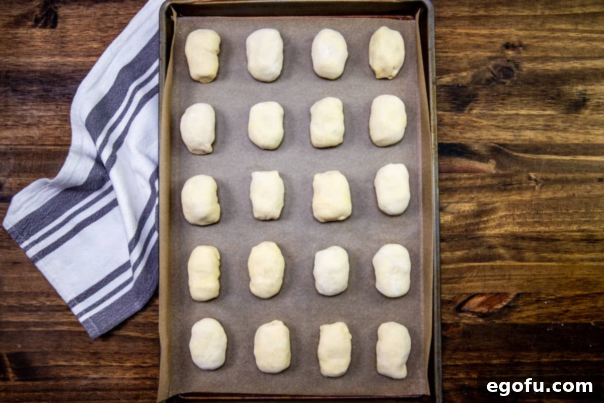 Sausage Rolls with Flaky Pastry 9 Sausage rolls wrapped in puff pastry, arranged on a baking sheet lined with parchment paper.