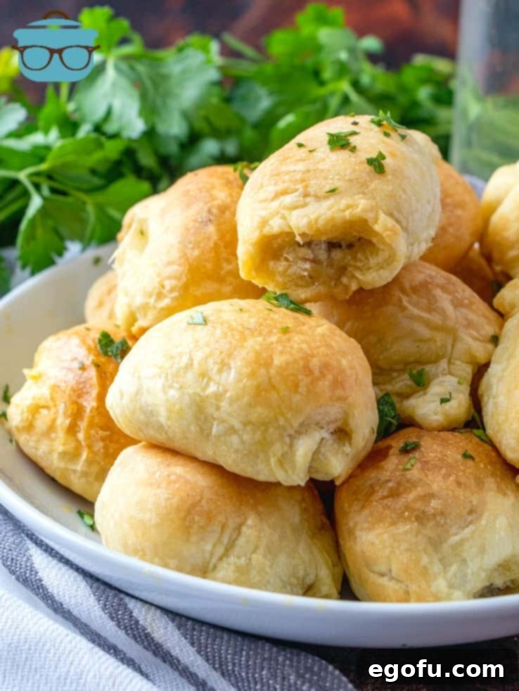 Sausage Rolls with Flaky Pastry 10 Delicious 3-Ingredient Puff Pastry Sausage Rolls stacked on a white plate, garnished with fresh parsley.