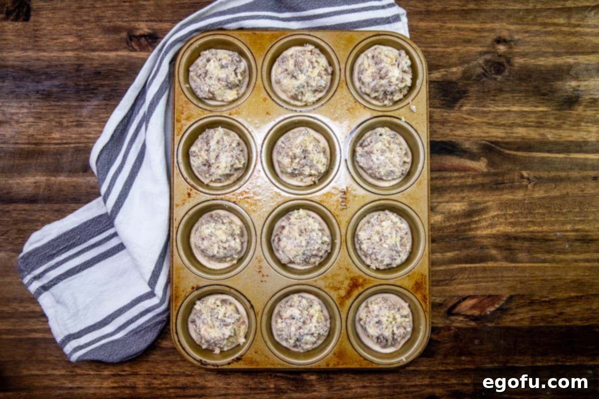 Cream cheese sausage mixture added to the tops of each refrigerated biscuit in a muffin tin.