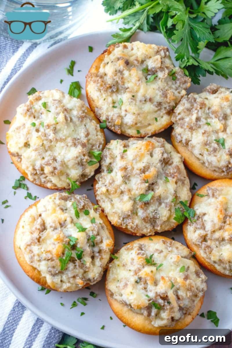 Cream Cheese Stuffed Sausage Biscuits topped with chopped fresh parsley displayed on a round white platter.