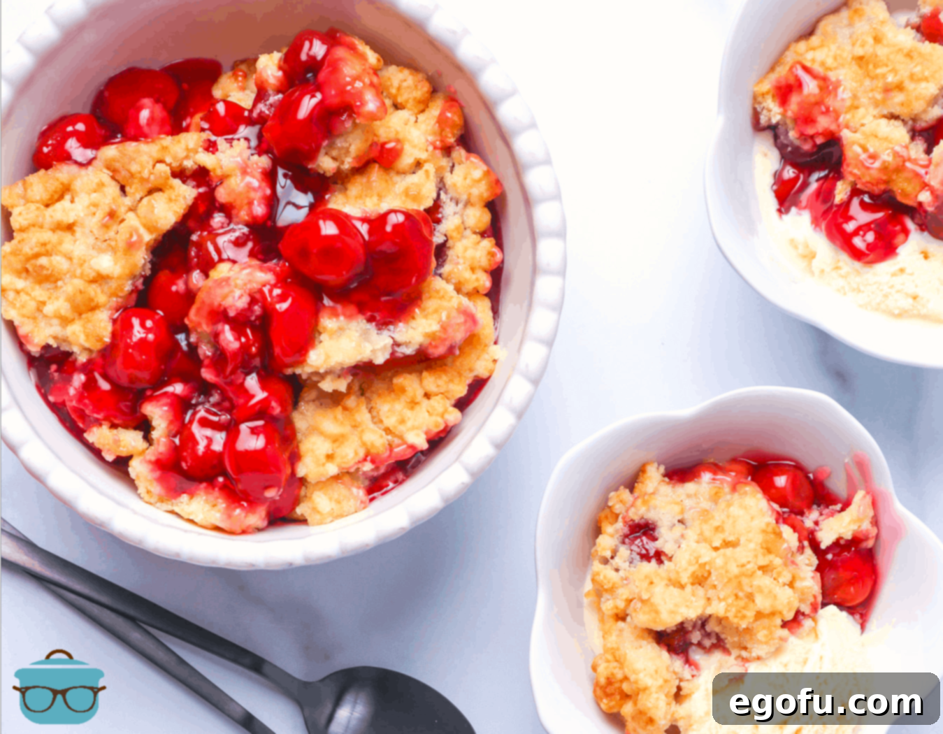 pictured, cherry cobbler served in three white bowls and scoops of vanilla ice cream.