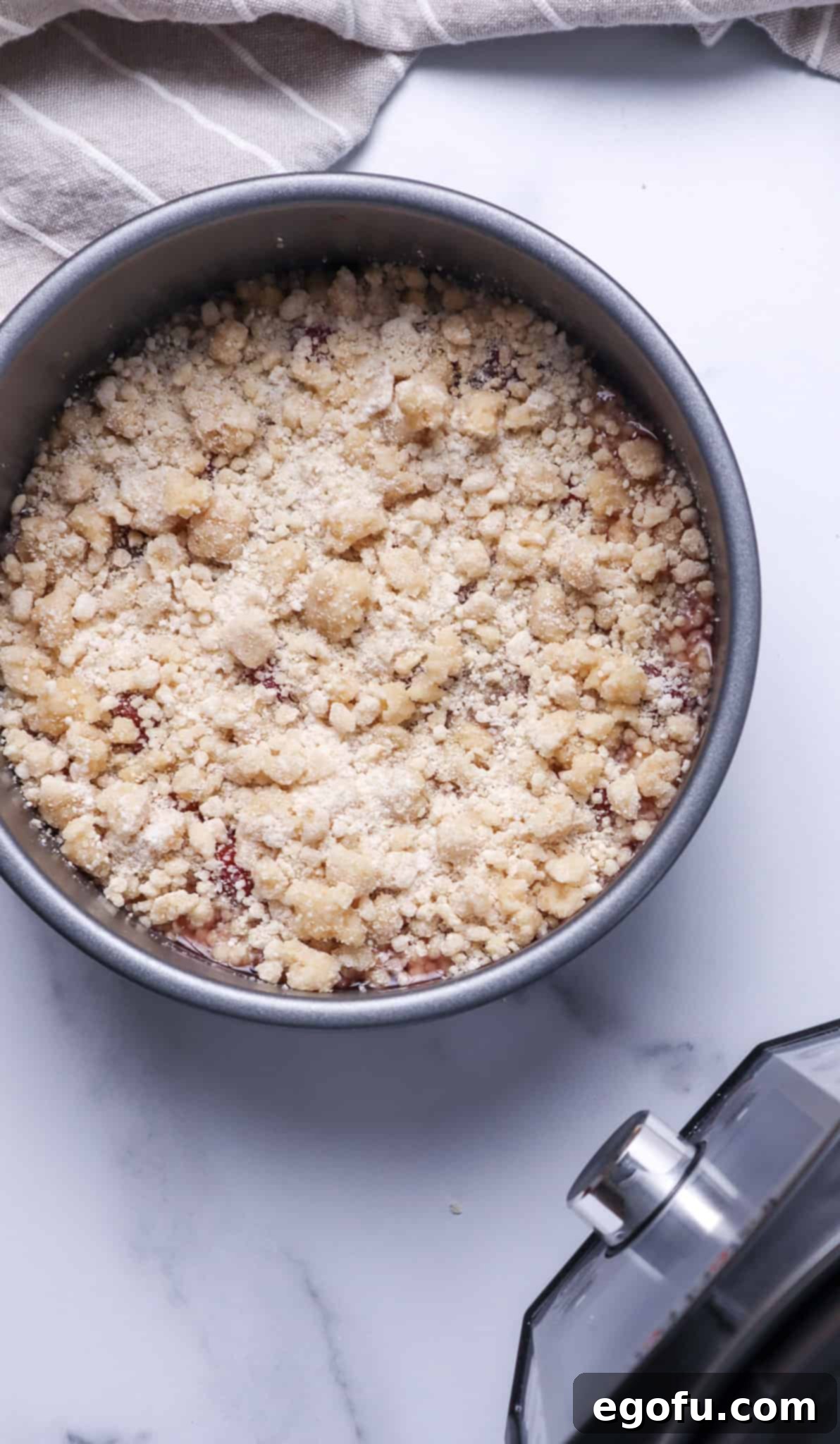 sprinkling cake mix mixture on top of cherry pie filling in a cake pan.