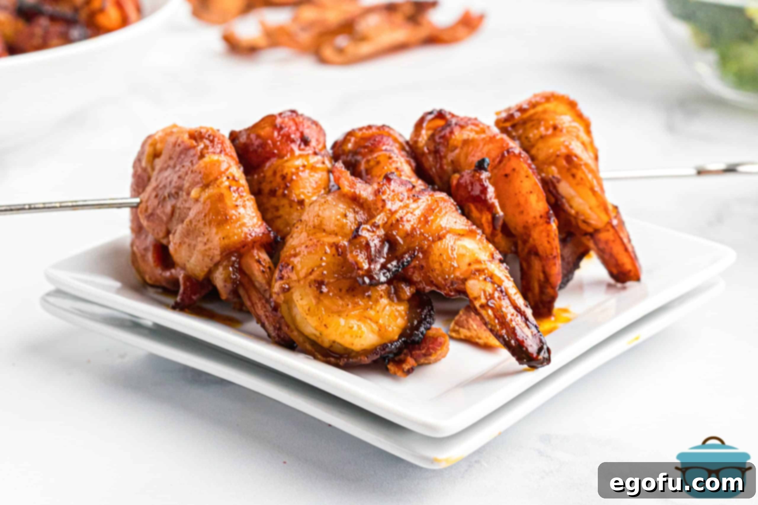 BBQ Bacon Wrapped Shrimp on a metal skewer on white plates.