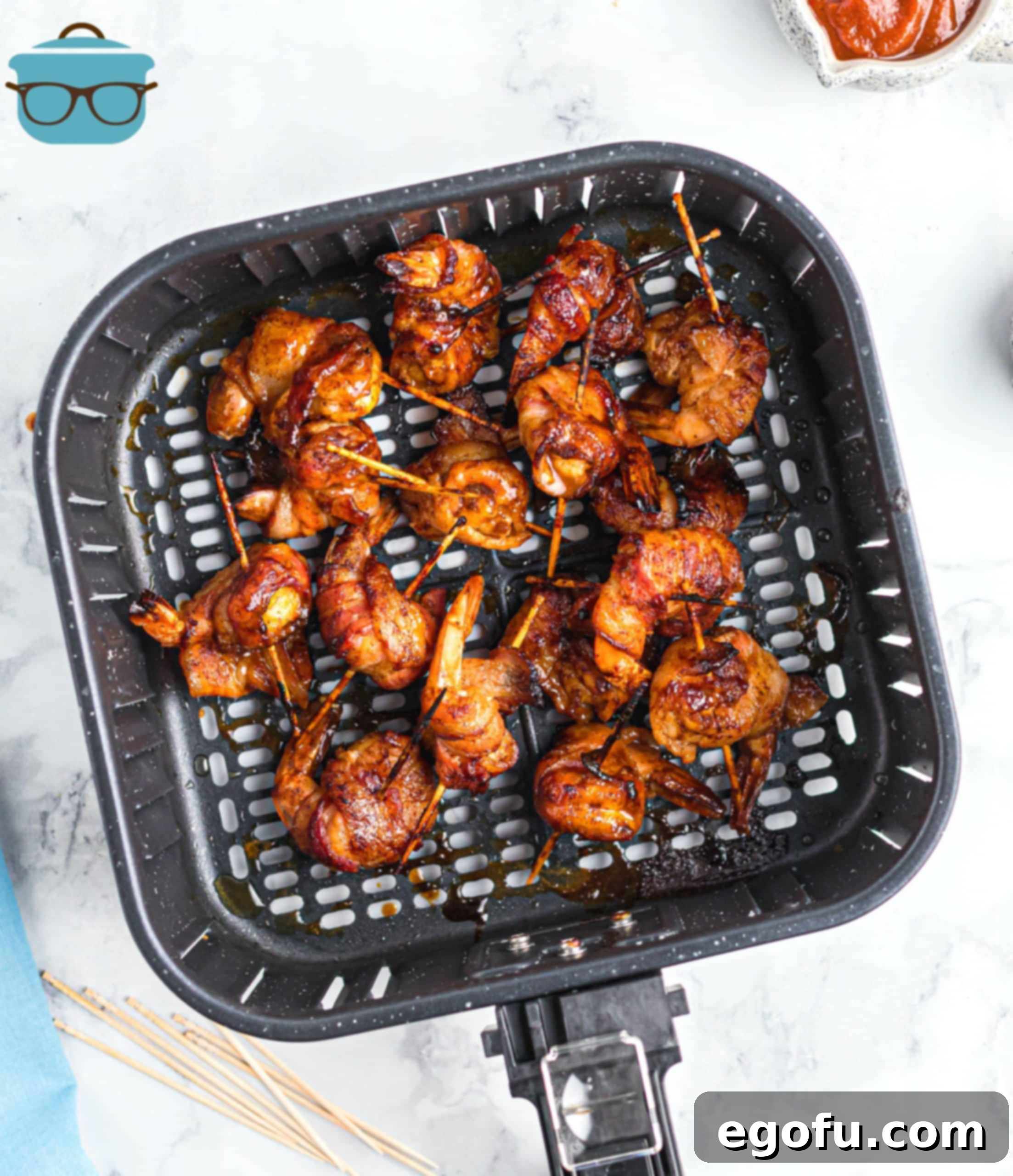 cooked bacon garlic shrimp shown in an air fryer basket.