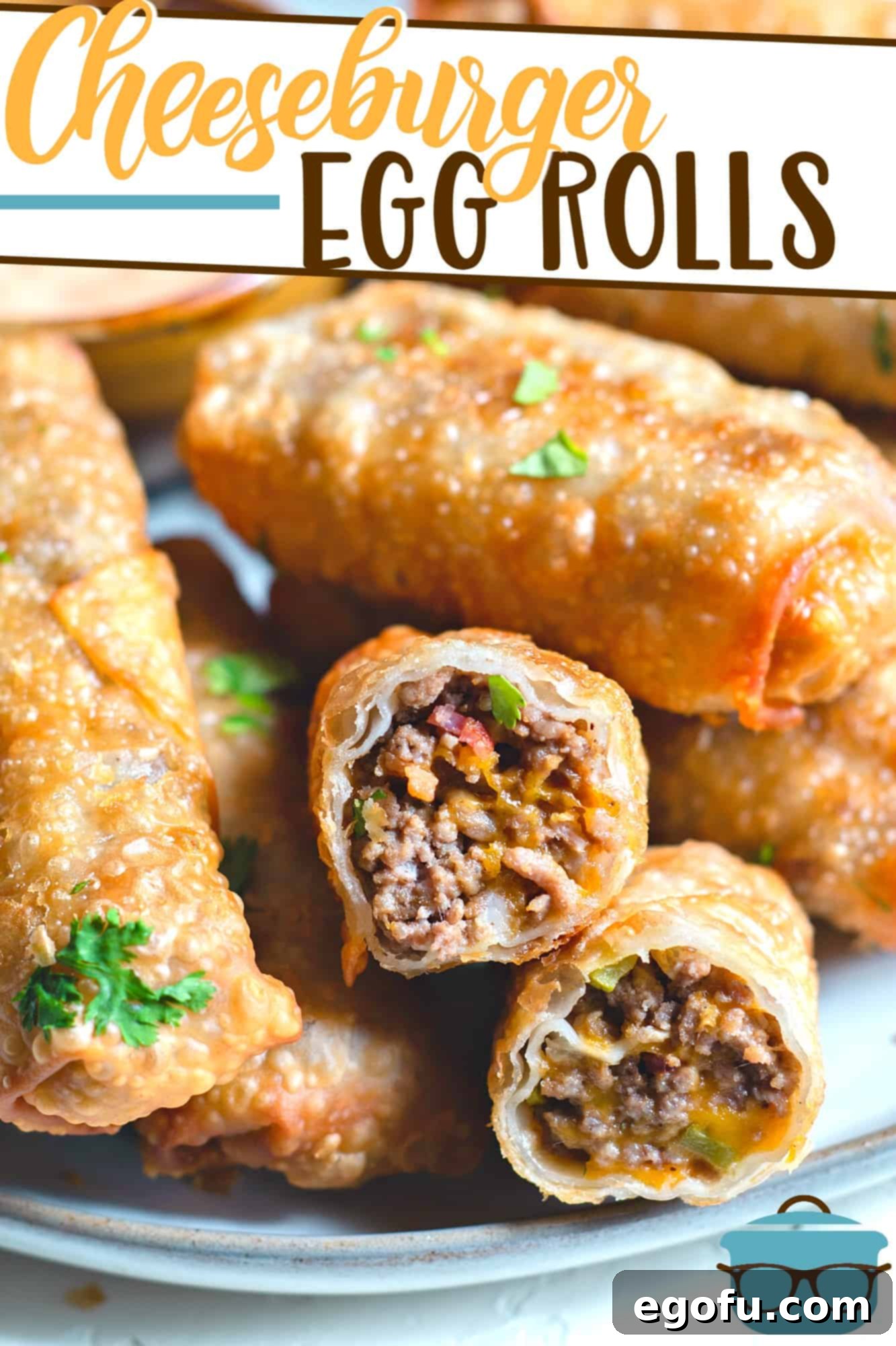 Crispy Cheeseburger Rolls 4 Bacon Cheeseburger Egg Rolls recipe from The Country Cook, shown stacked on a platter with one egg roll cut open to see the inside.