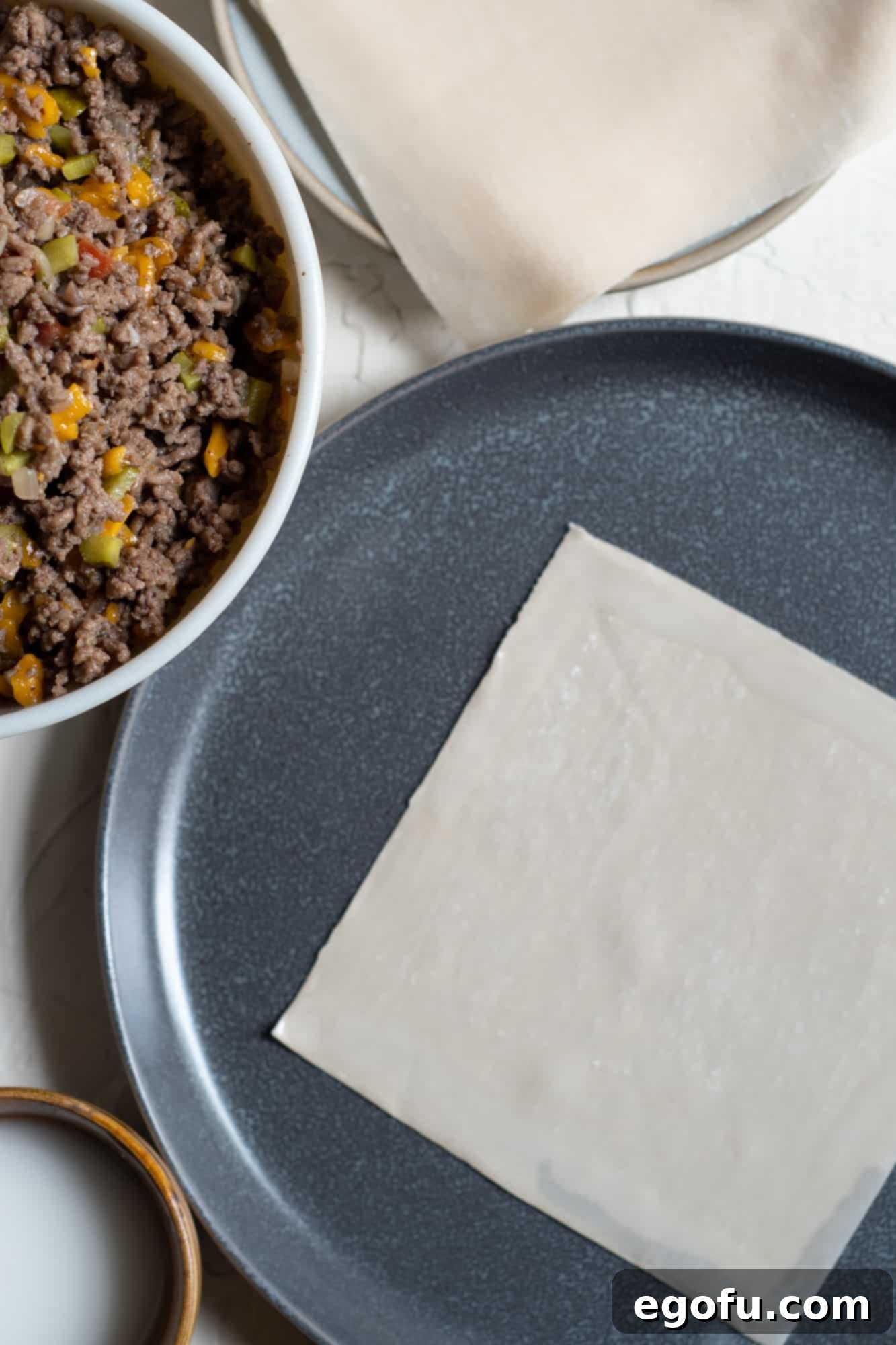 Crispy Cheeseburger Rolls 6 Adding cornstarch and water mixture to the edges of an egg roll wrapper to seal it.